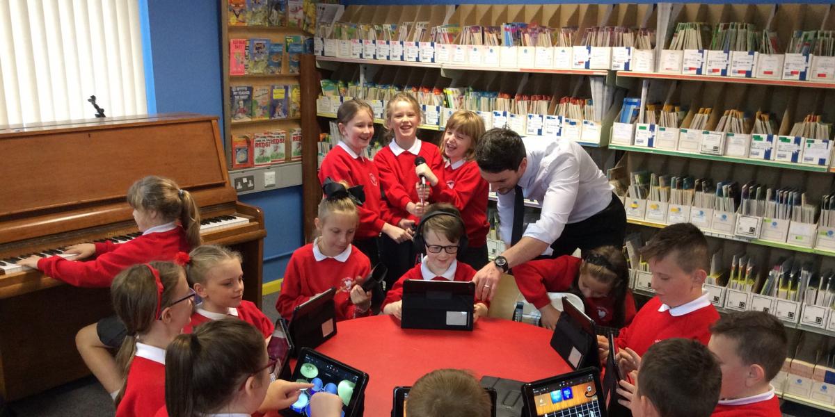 photo of children with tutor playing music on ipads