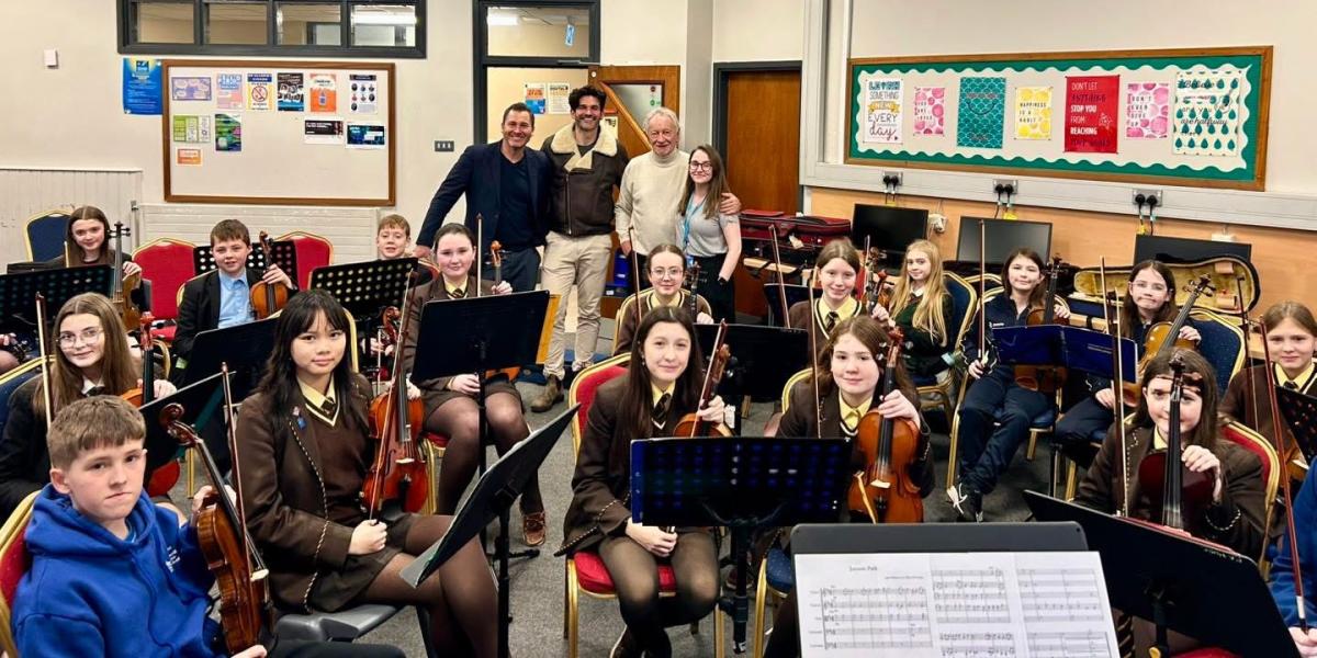 Phil Coulter with pupils holding instruments in a classroom