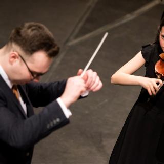 conductor and young violinist in concert