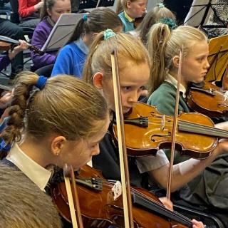 Violin section performing in Strule Theatre