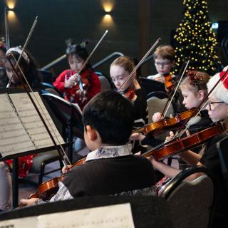 Children playing violins performing at a Christmas concert