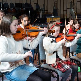 Children playing violins performing at a Christmas concert