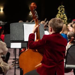 A child playing a double bass performing at a Christmas concert
