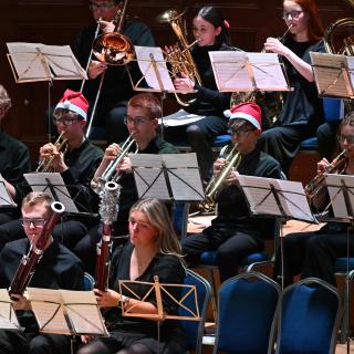 Children and young people playing brass instruments and bassoons at a concert.