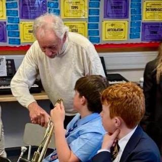 Phil Coulter speaking to two pupils in a hall