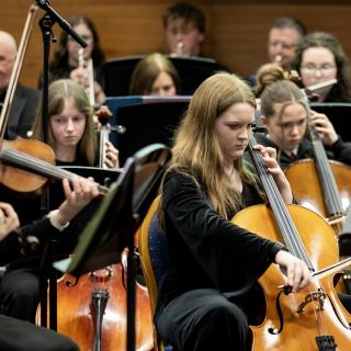 Young cellists performing in a concert