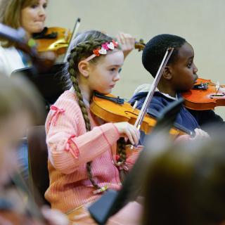 Young musicians performing in a string orchestra rehearsal