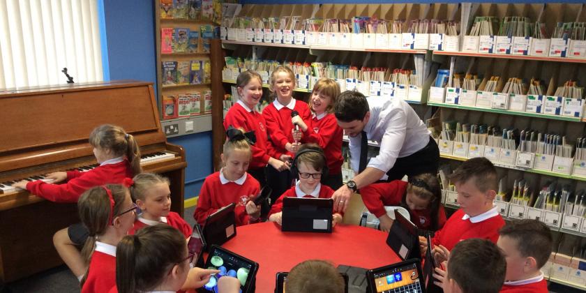 photo of children with tutor playing music on ipads