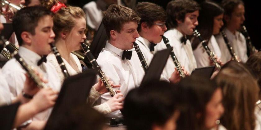 Woodwind section of youth orchestra in concert with brass section behind
